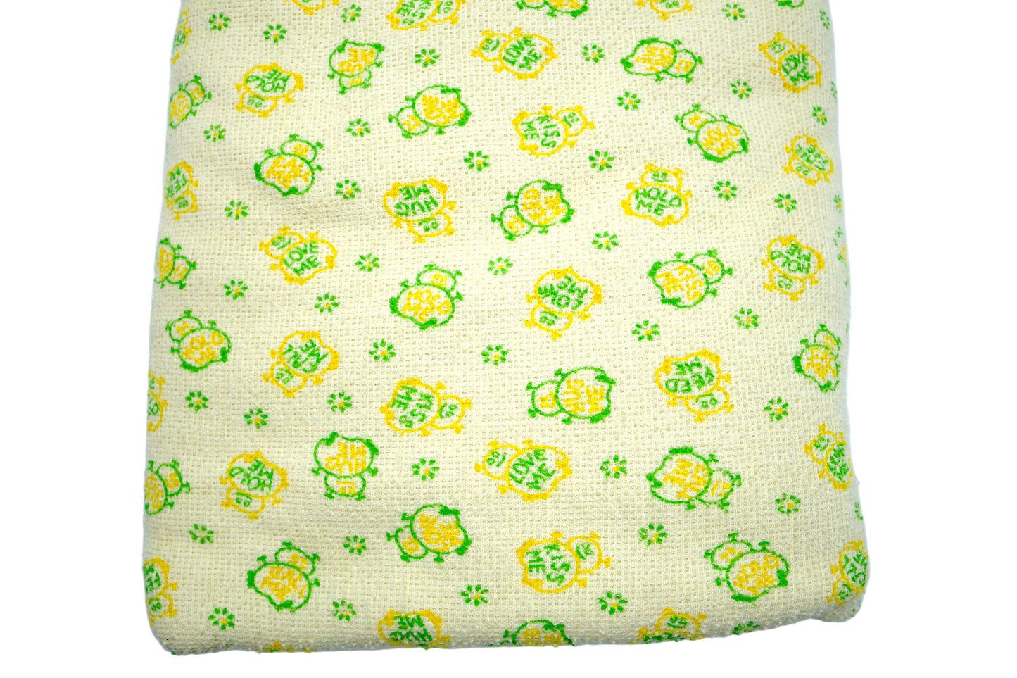 A folded piece of knit fabric with a floral pattern in yellow and green colors on a beige background.